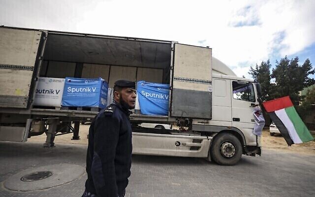 ضابط أمن فلسطيني يقف بجانب شاحنة تحمل لقاحات "سبوتنيك 5"، تبرعت بها دولة الإمارات العربية المتحدة، في مستودع تبريد في مدينة غزة، 26 يناير، 2022. (Mahmud HAMS / AFP)