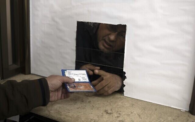رجل فلسطيني يسلم بطاقة هويته المؤقتة لموظف الشؤون المدنية للحصول على وثيقة تسجيله المعتمد رسميا، في مدينة غزة، 3 يناير، 2022. (AP Photo / Khalil Hamra)