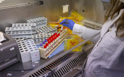 عاملون صحيون يجرون اختبارات على فحوصات PCR لتشخيص فيروس كورونا في مختبر تابع لصندوق المرضى كلاليت في القدس، 10 يناير، 2022.  (Olivier Fitoussi/Flash90)