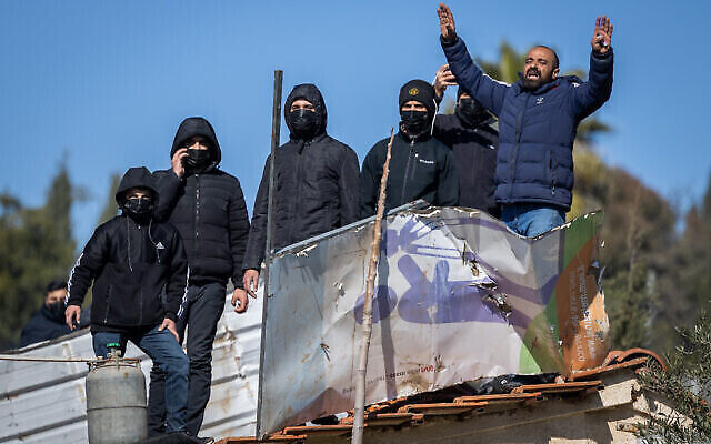 فلسطينيون يحملون اسطوانات الغاز يقفون على سطح منزل أخلته القوات الخاصة الإسرائيلية في حي الشيخ جراح بالقدس الشرقية، 17 يناير، 2022. (Yonatan Sindel / Flash90)