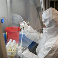 فنيون يجرون اختبارا تشخيصيا لكوفيد-19 في مختبر في فرع "لئوميت" للخدمات الصحية في أور يهودا، 21 يناير، 2022. (Yossi Zeliger / Flash90)