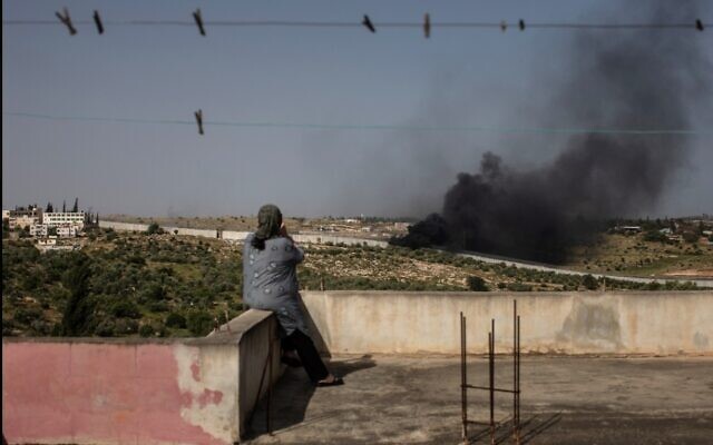 ميسون سويطي (54 عاما)، فلسطينية من سكان بلدة بيت عوا، تجلس على سطح منزلها وتشاهد حرق النفايات الإلكترونية والقمامة بالقرب من الجدار الخرساني الذي يفصل قريتها عن إسرائيل، 26 أبريل، 2019. (Tamir Kalifa)