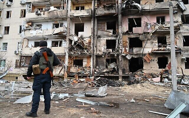 ضابط شرطة يقف في حراسة مبنى سكني متضرر في شارع كوشتسا، على مشارف العاصمة الأوكرانية كييف، حيث قيل إن قذيفة عسكرية سقطت، في 25 فبراير 2022 (GENYA SAVILOV / AFP)