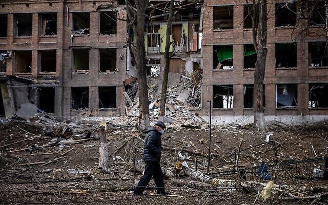 رجل يسير أمام مبنى مدمر بعد هجوم صاروخي روسي على بلدة فاسيلكيف ، بالقرب من كييف، 27 فبراير،  2022. (Dimitar DILKOFF / AFP)