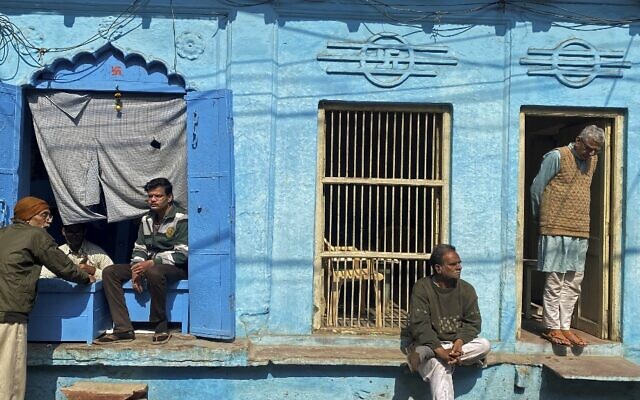 في هذه الصورة التي التقطت في 5 فبراير، 2022، يجلس أشخاص أمام منزل على طريق في ماثورا، الهند. (AJJAD HUSSAIN / AFP)