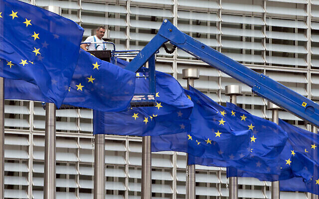 في صورة الملف هذه في 23 يونيو 2016، عامل على مصعد يعدل أعلام الاتحاد الأوروبي أمام مقر الاتحاد الأوروبي في بروكسل. (AP Photo / Virginia Mayo، File)