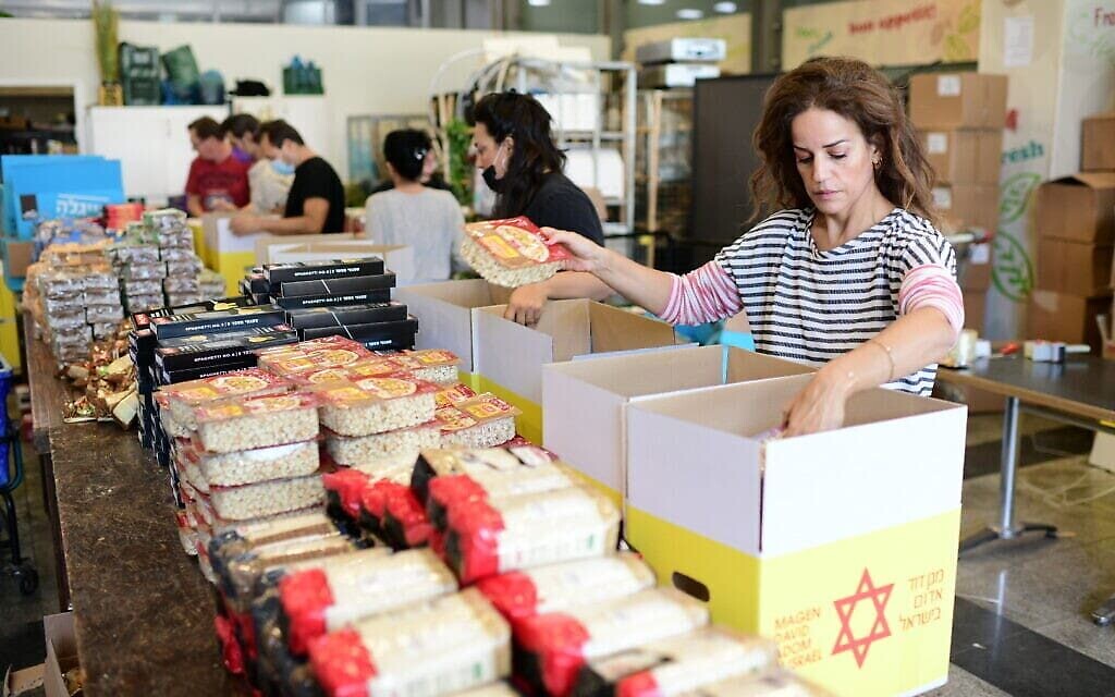 الفنانة الإسرائيلية غاليت غيئات مع متطوعين يعملون على تجهيز رزم مواد غذائية للمحتاجين، 24 نوفمبر، 2020. (Tomer Neuberg / Flash 90)