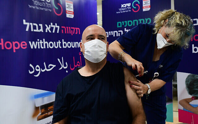 عامل رعاية صحية يتلقى لقاحا، في مركز شيبا الطبي في 5 يناير 2022 (Avshalom Sassoni / Flash90)