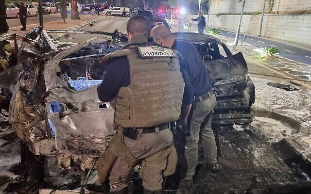 خبراء متفجرات ومحققون يفحصون موقع انفجار سيارة مفخخة في اشكلون،  13 فبراير، 2022، قُتل فيه رجل وأصيب اثنان آخران بجروح خطيرة. (الشرطة)
