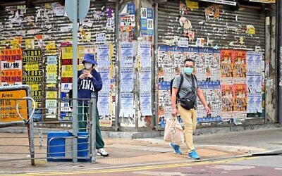مشاة يمرون أمام محل تجاري مغلق في هونغ كونغ في 7 مارس، 2022.   (Peter PARKS / AFP)