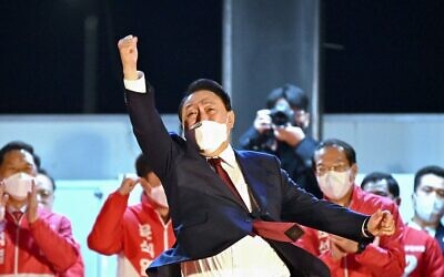 الرئيس الكوري الجنوبي المنتخب  يون سوك يول (وسط الصورة) من حزب "سلطة الشعب" يحيي مؤيديه أثناء تلقيه التهاني خارج مقر الحزب في سيول، 10 مارس، 2022. ( Jung Yeon-je / AFP)