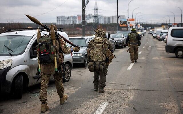 جنود أوكرانيون يحملون قذائف صاروخية وبنادق قنص أثناء سيرهم باتجاه مدينة إيربين، شمال غرب كييف،  13 مارس، 2022. ( Dimitar DILKOFF / AFP)