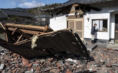 رجل يسير أمام مطعمه المتضرر في شيروشي بمقاطعة مياجي في 17 مارس 2022، بعد زلزال بقوة 7.3 درجات ضرب شرق اليابان في الليلة السابقة.  ( Charly TRIBALLEAU / AFP)
