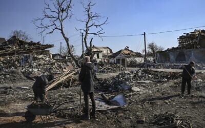 أشخاص يزيلون حطام المنازل المدمرة بعد قصف قرية كراسيليفكا شرقي كييف في 20 مارس 2022، بينما تحاول القوات الروسية تطويق العاصمة الأوكرانية.   ( Aris Messinis / AFP)