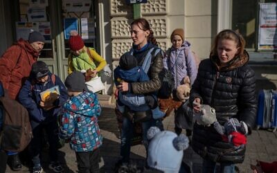 نساء يقفن مع أطفالهن خارج محطة السكك الحديدية الرئيسية في برزيميسل، جنوب شرق بولندا، بالقرب من الحدود البولندية الأوكرانية ، حيث ينتظر اللاجئون من أوكرانيا ركوب الحافلات إلى وجهات أخرى في بولندا،  24 مارس، 2022،  في أعقاب الغزو الروسي لأوكرانيا. (Angelos Tzortzinis / AFP)