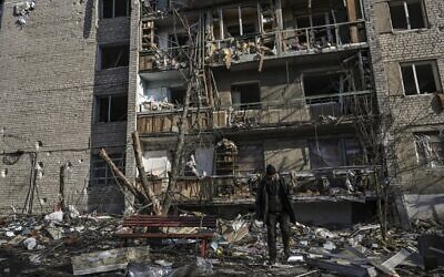 رجل يسير أمام مبنى سكني دمره قصف في خاركيف في 25 مارس 2022، أثناء الغزو العسكري الروسي لأوكرانيا. ( Aris Messinis / AFP)
