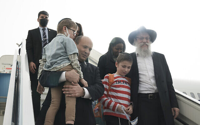 رئيس الوزراء نفتالي بينيت، وسط الصورة، يرحب بمجموعة من الأيتام من دار الأيتام "ألوميم" في مدينة جيتومير الأوكرانية، لدى وصولهم إلى إسرائيل في مطار بن غوريون، 6 مارس، 2022. (Maya Alleruzzo / AP)
