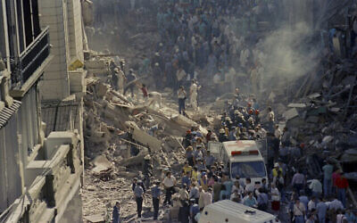 رجال إطفاء وعمال إنقاذ يسيرون عبر الأنقاض بعد هجوم على سفارة إسرائيل في بوينس آيرس، الأرجنتين، في 17 مارس 1992 (Don Rypka / AP)