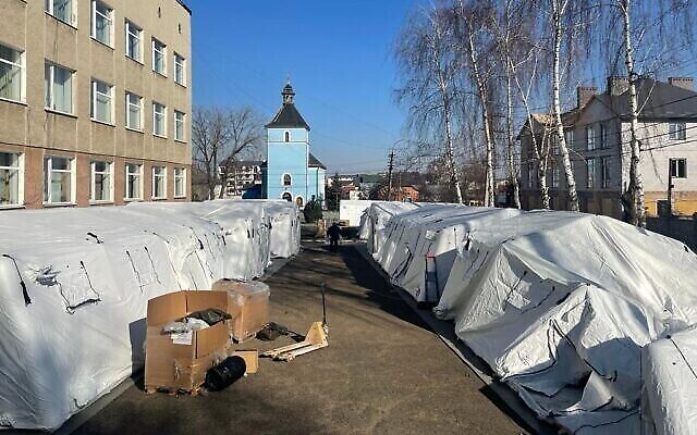عمال أوكرانيون يبنون خياما للمستشفى الميداني الإسرائيلي الجاري إنشاؤه في موستيسكا ، أوكرانيا، 18 مارس، 2022. (Carrie Keller-Lynn/The Times of Israel)