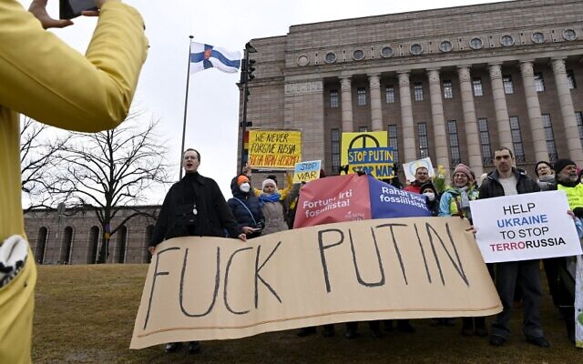 متاظرون يحملون لافتة كتب عليها "تبا لبوتين" في إشارة إلى الرئيس الروسي فلاديمير بوتين من أمام البرلمان الفنلندي في هلسنك ، فنلندا، في 8 أبريل 2022 حيث ألقى الرئيس الأوكراني فولوديمير زيلينسكي كلمة أمام أعضاء البرلمان الفنلندي عبر رابط فيديو. ( Emmi Korhonen / Lehtikuva / AFP) / Finland OUT