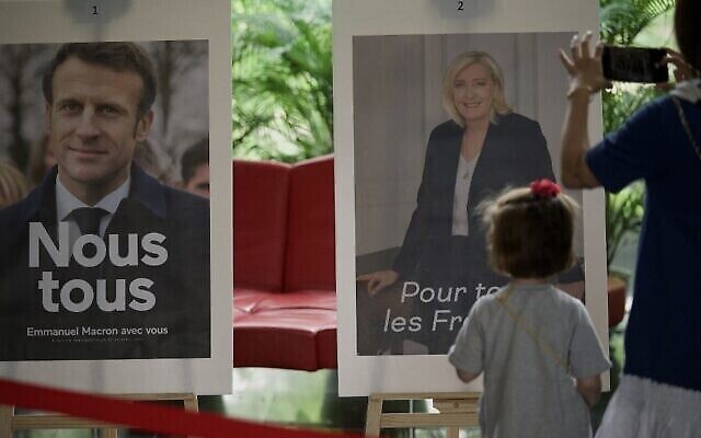 عرض صورتي المرشحين إيمانويل ماكرون (إلى اليسار) ومارين لوبن خلال الجولة الثانية من التصويت في انتخابات الرئاسة الفرنسية في السفارة الفرنسية في بكين، 24 أبريل، 2022. (Noel Celis / AFP)