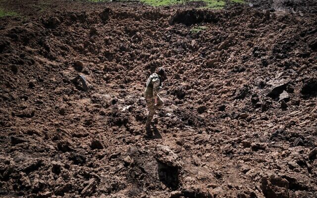 جندي أوكراني يتفقد حفرة بعد هجوم صاروخي روسي مزعوم في بووداروف، شرق أوكرانيا، في 25 أبريل 2022، وسط الغزو الروسي لأوكرانيا. (Yasuyoshi CHIBA / AFP)