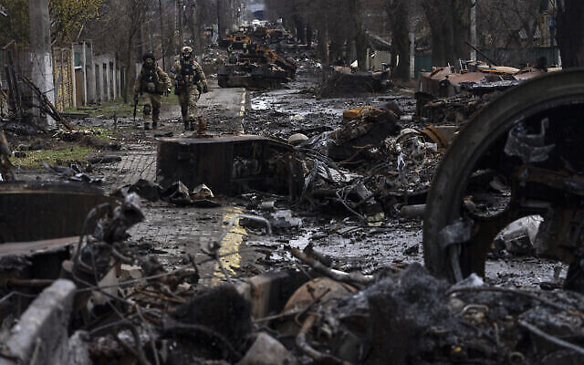 جنود يسيرون وسط الدبابات الروسية المدمرة في بوتشا، في ضواحي كييف، أوكرانيا، 3 أبريل 2022 (AP Photo / Rodrigo Abd)