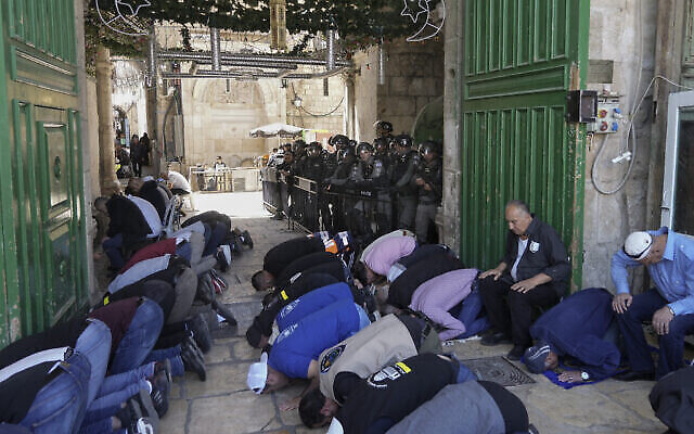 قوات الأمن الإسرائيلية تقوم بالحراسة بينما يؤدي رجال فلسطينيون صلاة الجمعة الثانية من شهر رمضان المبارك أمام قبة الصخرة في الحرم القدسي في البلدة القديمة بالقدس، 15 أبريل، 2022. (AP / Mahmoud إلين)