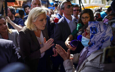 زعيمة اليمين المتطرف الفرنسية مارين لوبن، إلى يسار الصورة ، تتحدث إلى امرأة خلال حملتها الانتخابية في سوق في بيرتوي، جنوب فرنسا، 15 أبريل، 2022. (AP / Daniel Cole، File)