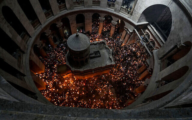 حجاج مسيحيون يحملون الشموع أثناء تجمعهم خلال "سبت النور" في كنيسة القيامة، حيث يعتقد العديد من المسيحيين أن المسيح قد صلب ودفن وقام من الموت، في البلدة القديمة بالقدس، 23 أبريل، 2022. (AP Photo/ Tsafrir Abayov)