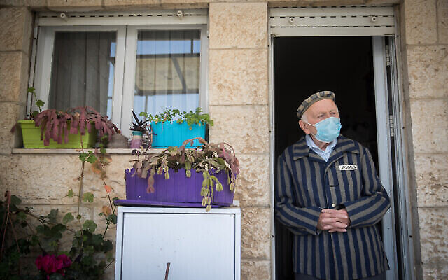توضيحية: جوزيف كلاينمان، ناج من المحرقة يبلغ من العمر 90 عاما من الناجين من معكسر الموت في أوشفيتس وداخاو، يرتدي كمامة للوجه وهو يقف عند شرفة منزله في القدس، خلال يوم الكارثة والبطولة، 21 أبريل، 2020. (Yonatan Sindel / Flash90) )