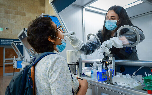 فنية طبية تقوم باختبار مسافرة لفيروس كورونا في مطار بن غوريون، 30 يونيو 2021 (Avshalom Sassoni / Flash90)