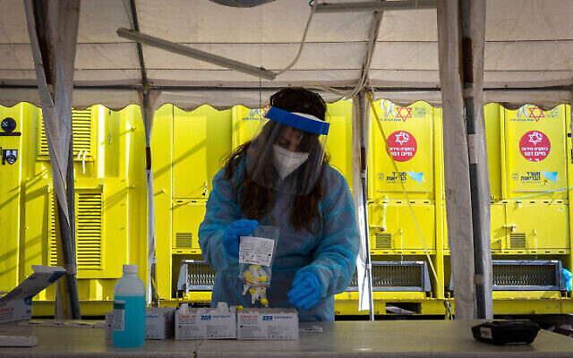 عاملة في نجمة داوود الحمراء تأخذ اختبار مستضد سريع لـفحص فيروس كورونا من إسرائيليين، في  سيارة تابعة لنجمة داوود الحمراء في القدس، في 22 مارس 2022 (Olivier Fitoussi / Flash90)