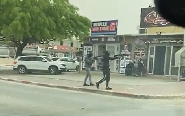 لقطة شاشة من مقطع فيديو يظهر على ما يبدو مسلحين يفتحون النار باتجاه متجر في رهط، 24 أبريل، 2022. (Screen grab / Kan)