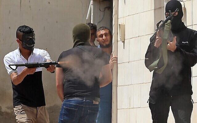 مسلح فلسطيني ملثم أطلق النار من سلاح آلي خلال اشتباكات مع قوات الأمن الإسرائيلية في مدينة جنين بالضفة الغربية، 13 مايو 2022 (Jaafar Ashtiyeh / AFP)