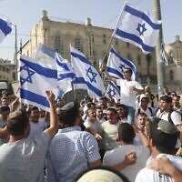 إسرائيليون يلوحون بالأعلام الإسرائيلية خلال مسيرة "يوم أورشليم" في القدس، 10 مايو، 2021. (AP Photo / Ariel Schalit)