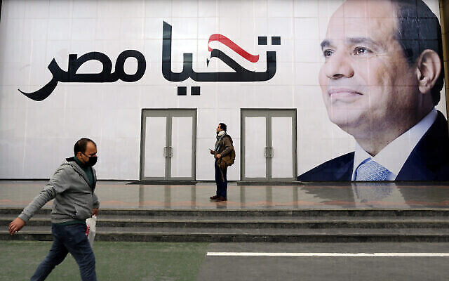 رجل يسير أمام لوحة إعلانية للرئيس المصري عبد الفتاح السيسي، مكتوب عليها بالعربية "تحيا مصر"، في معرض القاهرة الدولي للكتاب، القاهرة، مصر، الخميس 27 يناير 2022. (AP /Amr Nabil)