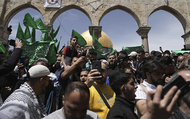 فلسطينيون يرددون هتافات ويلوحون بأعلام حماس بعد صلاة الجمعة خلال شهر رمضان المبارك، بعد ساعات من اشتباكات بين الشرطة الإسرائيلية مع المتظاهرين في مجمع المسجد الأقصى، في البلدة القديمة بالقدس، 22 أبريل، 2022. (AP Photo / Mahmoud Elean) )