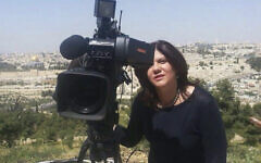 في هذه الصورة غير المؤرخة التي قدمتها شبكة الجزيرة الإعلامية، تقف شيرين أبو عاقلة ، الصحافية في شبكة الجزيرة، بجانب كاميرا تلفزيونية وفي الخلفية تظهر البلدة القديمة في القدس.  (Al Jazeera Media Network via AP)