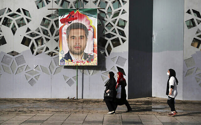 أشخاص يمشون أمام لافتة تظهر العقيد في الحرس الثوري الإيراني حسن صياد خضيري الذي قُتل يوم الأحد، قبل مراسم جنازته، في طهران، إيران، 24 مايو 2022 (AP Photo / Vahid Salemi)