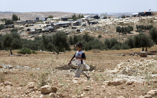 طفل فلسطيني يسير وفي الخلفية تظهر قريته سوسيا في المنطقة C من الضفة الغربية، 24 يوليو، 2015. (AP / Nasser Nasser)