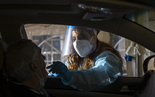 عاملة صحية في نجمة داؤود الحمراء تأخذ عينة في مجمع اختبارات كورونا في القدس، في 22 مارس 2022 (Olivier Fitoussi / Flash90)