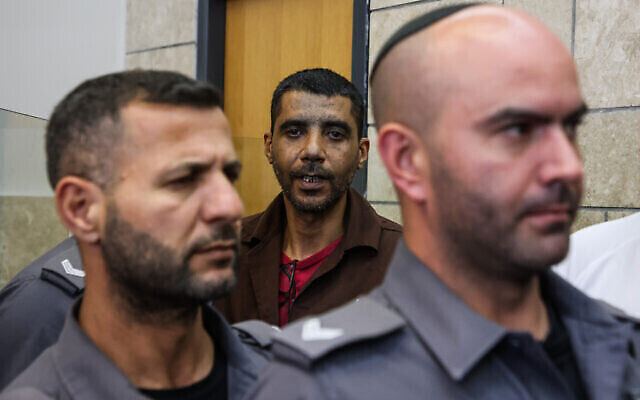 زكريا زبيدي (وسط الصورة) الذي فر من سجن جلبوع شديد الحراسة مع أسرى آخرين ، محاطا بحراس السجن لدى وصوله لحضور جلسة استماع في مدينة الناصرة شمال إسرائيل، 22 مايو، 2022.(Oren Ziv / POOL)