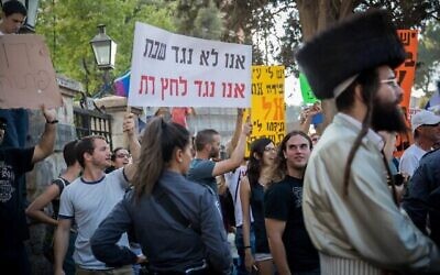 متظاهرون علمانيون إسرائيليون يرددون هتافات في القدس في 12 أغسطس، 2017، خلال مظاهرة لليهود الحريديم ضد الشركات التي تعمل أيام السبت في المدينة. كُتب على اللافتة "لسنا ضد السبت، نحن ضد الضغط الديني". (Yonatan Sindel / Flash90)