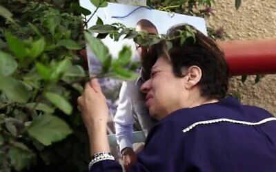 سامية خوري تبكي في نصب تذكاري مرتجل أقيم تخليدا لذكرى ابنها أمير خوري، في المكان الذي قُتل فيه أثناء رده على هجوم وقع في 29 مارس في بني براك، في مقطع فيديو بثته أخبار القناة 12 في 3 مايو، 2022.(Screen capture: Channel 12)