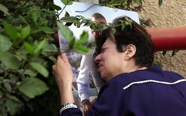 سامية خوري تبكي في نصب تذكاري مرتجل أقيم تخليدا لذكرى ابنها أمير خوري، في المكان الذي قُتل فيه أثناء رده على هجوم وقع في 29 مارس في بني براك، في مقطع فيديو بثته أخبار القناة 12 في 3 مايو، 2022.(Screen capture: Channel 12)