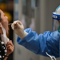 توضيحية: عامل صحي يأخذ عينة عن طريق المسحة من امرأة في منطقة هوانغبو في شنغهاي في 1 يونيو 2022، بعد تخفيف قيود كوفيد-19 في المدينة بعد إغلاق لمدة شهرين. (Hector RETAMAL / AFP)