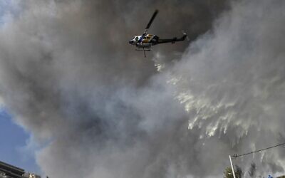 طائرة هليكوبتر تلقي المياه على النيران المشتعلة في منطقة سكنية في بانوراما فولاس، جنوب أثينا، في 4 يونيو، 2022. (Louisa GOULIAMAKI / AFP)