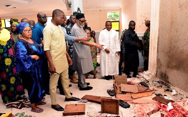 حاكم ولاية أوندو روتيمي أكريدولو (الثالث من اليسار) يشير إلى الدماء التي تلوح الأرضبعد هجوم شنه مسلحون على كنيسة القديس فرانسيس الكاثوليكية في مدينة أوو ، جنوب غرب نيجيريا في 5 يونيو، 2022. (Photo by AFP)