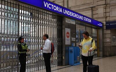 شرطية تتحدث إلى أحد الركاب عند المدخل المغلق لمحطة مترو أنفاق فيكتوريا في لندن في 6 يونيو 2022، خلال إضراب استمر 24 ساعة  لما يقرب من 4000 من موظفي مترو أنفاق لندن. (Photo by Hollie Adams / AFP)